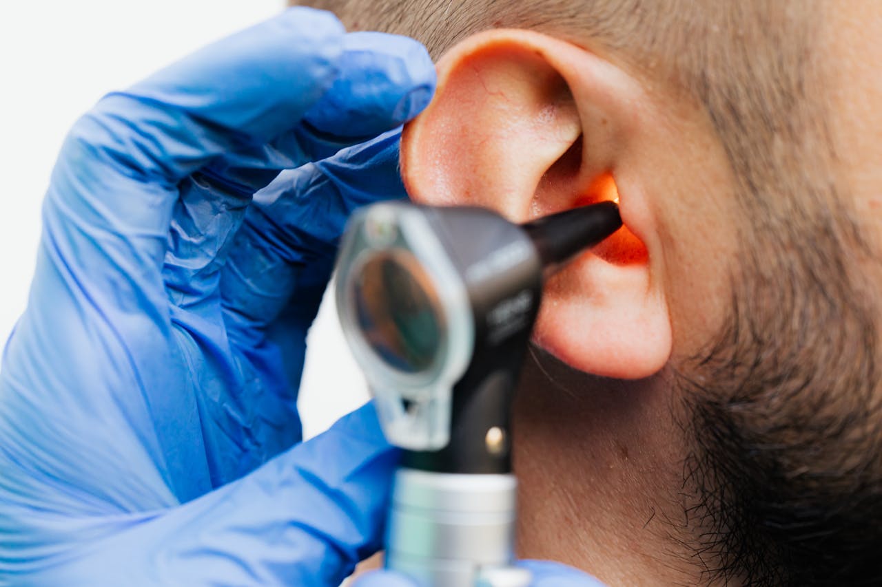 heros-img Close-up of a doctor using an otoscope to examine a patient's ear in a clinical setting.